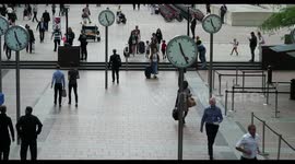 crowds walking in canary wharf, london docklands, with the famous clocks
