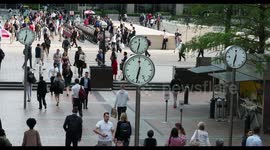 crowds walking in canary wharf, london docklands, with the famous clocks