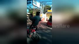 Indonesian man rides bike by sitting backwards on handlebars