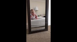 Baby tumbled over smiling at herself in the mirror