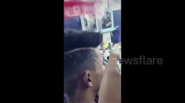 Barber gives his customer a stylish hair trim using a cigarette lighter