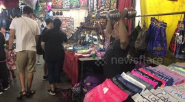Market stall trader lifts dumbbells in between serving tourists in Thailand