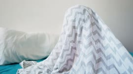 adorable small baby girl playing hide and peek a bo under a bed sheet
