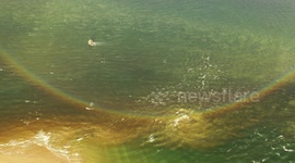 Magnificent Rainbow Reflection On Sea With Swirling Sand In Tidal Currents - Drone View