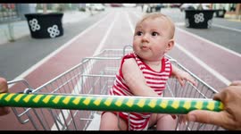 adorable small baby girl being pushed around outside in a shopping trolley