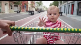adorable small baby girl being pushed around outside in a shopping trolley
