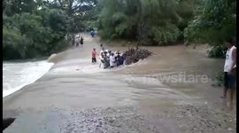 Locals carry motorcycle across flooded river following tropical storm in the Philippines