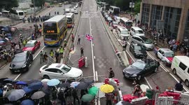 An old lady waving the Union Jack at the frontline between protests and police, while protesters are helping to divert the traffic.