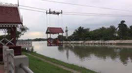 Thai Buddhist monks, take a cable car across a river to get to their temple.