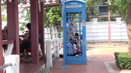 Thai kids playing in a public phone box.