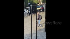 Newsflare Edit - Man ties bin bags around legs as he wades through London floodwater