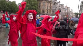 The Red Brigade raise hands in solidarity with Extinction Rebellion climate change protesters in Trafalgar Square