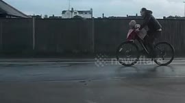Toddler  riding on handlebar of  dads bicycle  ,very dangerous UK cyclist