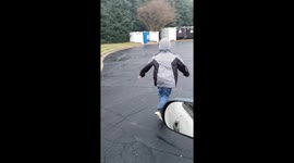 Boy sliding on pavement in the rain and slips at the end