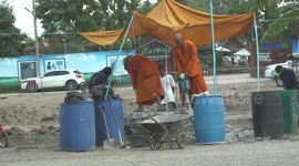 Buddhist monks in orange robes working with jack hammers, at Ayutthaya, Thailand.