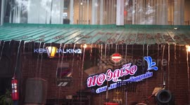 Torrential rain falls on tables and chairs in a restaurant with no roof, at Ayutthaya, Thailand.