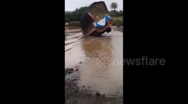 Truck driver flips over on flooded road in west India