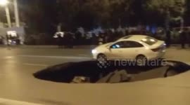 Car left overhanging sinkhole that opened up on Chinese road