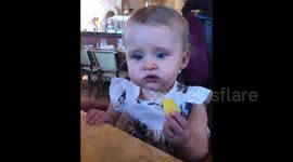 Baby girl eating a lemon for the first time