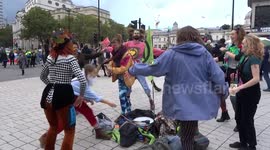 Phantasmagorical Extinction Rebellion clownade panto in Trafalgar Square next to Charles I statue with Change is Now placard on it
