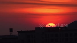 A sunrise over rooftops with satellite dishes in Bangkok.