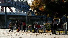 Autumn pedestrian street view with people walking and sitting on bench.