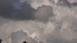 An airplane flies through a cloudy sky in Thailand.