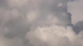 Closeup of an airplane flying across a cloudy sky, in Thailand.