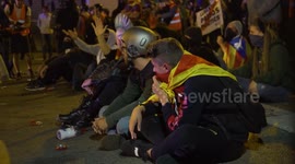 Pro Independence Protesters sit in front of line of police.