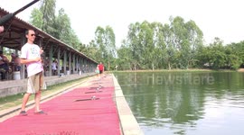A man reels in a big fish at a fishing pond in Thailand.