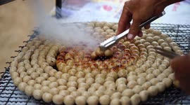 A street vendor cooking sausages in Thailand.