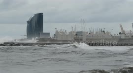 slow motion shot of barcelona's beaches with large waves and surfers out in the sea