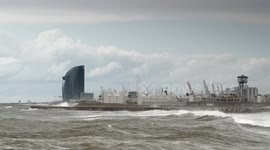 slow motion shot of barcelona's beaches with large waves and surfers out in the sea