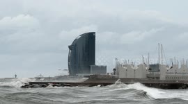 slow motion shot of barcelona's beaches with large waves and surfers out in the sea