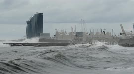 slow motion shot of barcelona's beaches with large waves and surfers out in the sea
