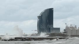 slow motion shot of barcelona's beaches with large waves and surfers out in the sea