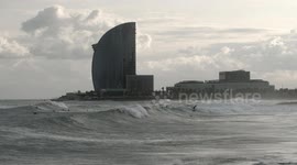 slow motion shot of barcelona's beaches with large waves and surfers out in the sea