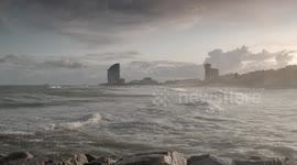 slow motion shot of barcelona's beaches with large waves and surfers out in the sea