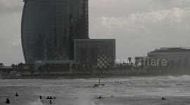 slow motion shot of barcelona's beaches with large waves and surfers out in the sea