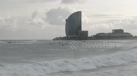 slow motion shot of barcelona's beaches with large waves and surfers out in the sea