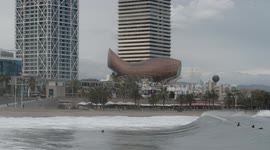 slow motion shot of barcelona's beaches with large waves and surfers out in the sea