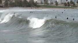 slow motion shot of barcelona's beaches with large waves and surfers out in the sea