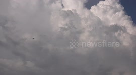 An airplane rises up through a white cloudy sky.