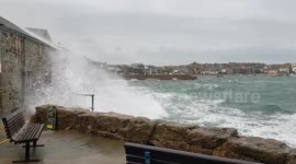 Waves crash against seawall in Cornwall, UK