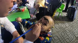 A father in Vietnam draws strange shapes and funny on a baby's face to attend the Halloween festival