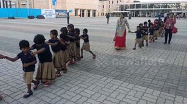 Adorable kindergarten children walk in line with hands on each other shoulder in Hyderabad,India