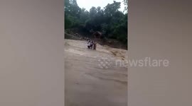 Residents help each other to cross flooded river after typhoon hits the Philippines
