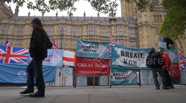 Pedestrians in slow motion pass Brexit signs at Parliamemt