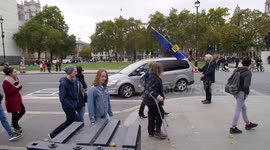 Parliament MP arrives in car with  Brexit protester waving flag slow motion