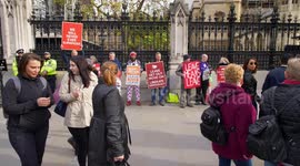 Pedestrians walk past Brexiteers holding leave signs